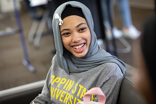 A young student smiles while conversing with another