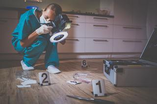 A female wearing protective gear photographs a crime scene