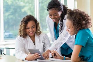 Female nursing students looking at a digital tablet before class.