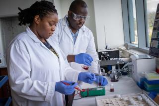 A female science student wearing a lab coat working in the lab